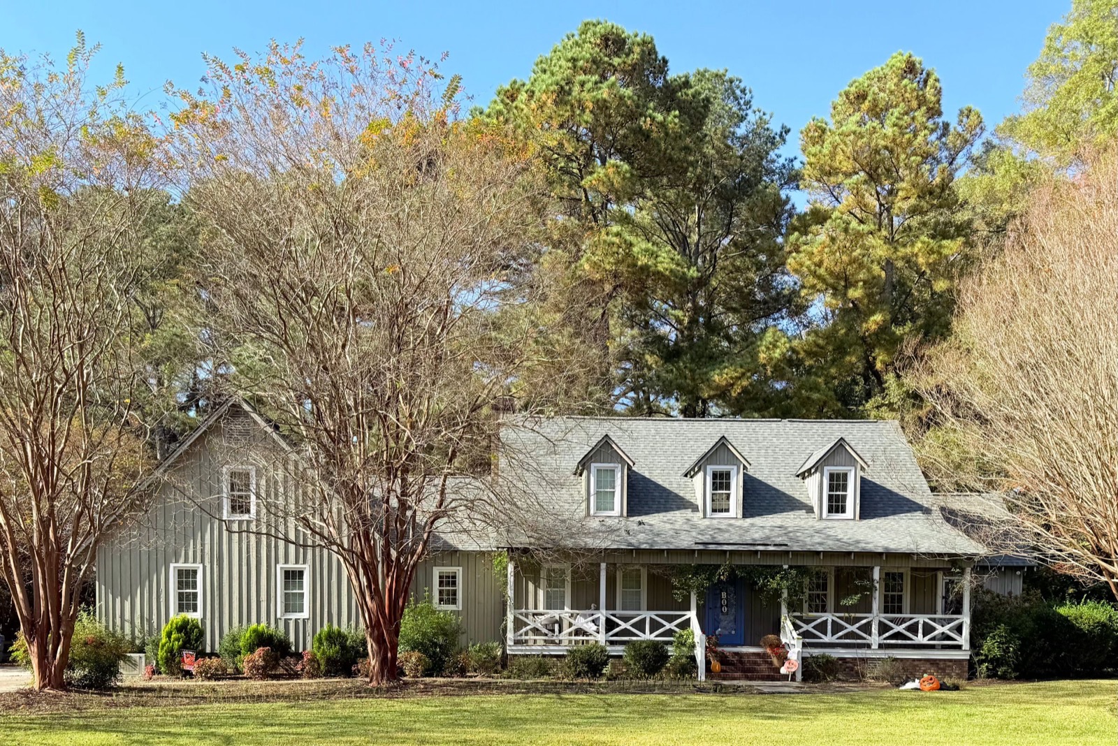 A farmhouse with a wrap-around porch framed by autumn foliage — the season Panhandle homeowners walk the maintenance checklist before the first freeze