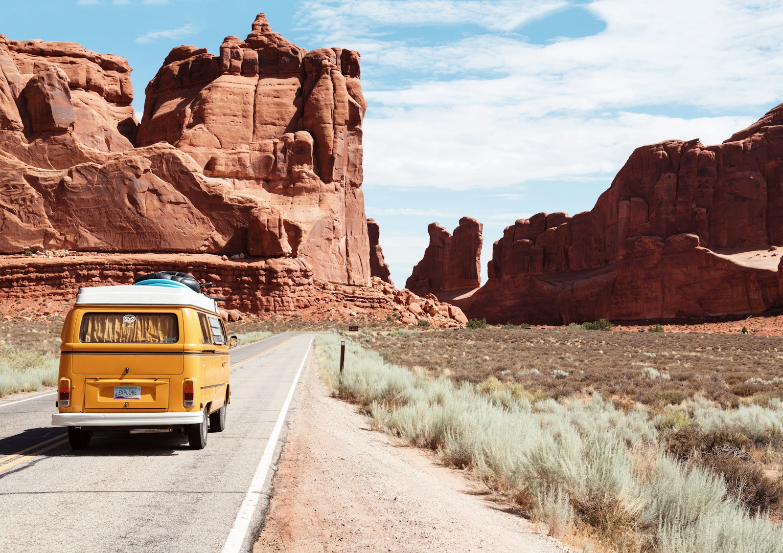 Vintage camper van on a desert highway under a clear blue sky